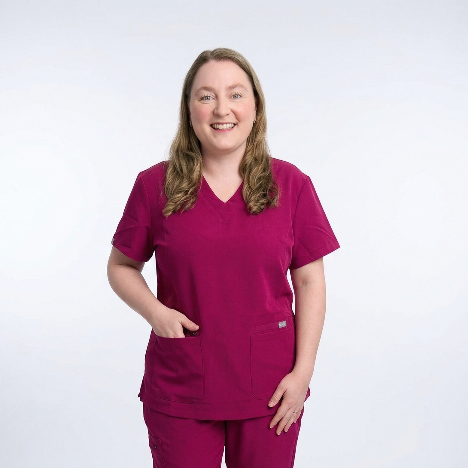 Person wearing a magenta scrub set on a white background